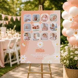 May include: A peach and white sign on a wooden easel, featuring a collage of baby photos. The sign reads "Mila my first year" with a date. Daisy graphics and a soft color palette create a celebratory theme, perfect for a baby's first birthday.