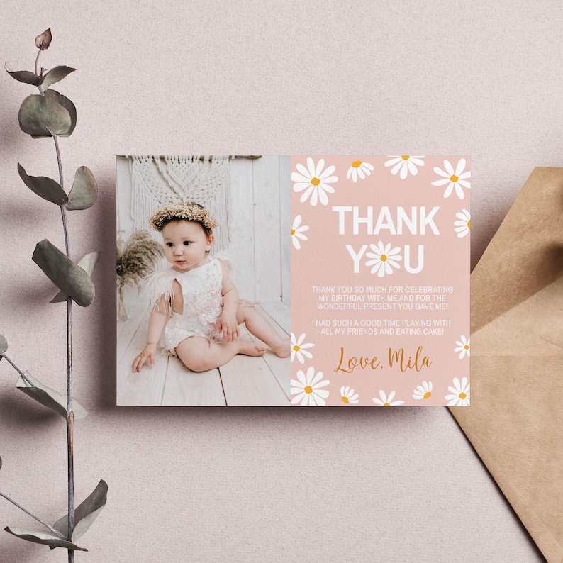 May include: A pink thank you card with white daisies and a photo of a baby girl wearing a white dress and a flower crown. The text on the card reads "Thank You" and "Love, Mila".