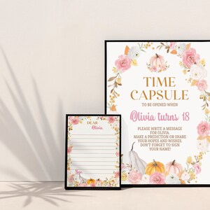 K&ouml;nnte beinhalten: Ein gro&szlig;es und ein kleines gerahmtes Schild mit einem Blumen- und K&uuml;rbiskranz-Design. Das gro&szlig;e Schild tr&auml;gt die Aufschrift: TIME CAPSULE TO BE OPENED WHEN Olivia turns 18. PLEASE WRITE A MESSAGE FOR OLIVIA. MAKE A PREDICTION OR SHARE YOUR HOPES.