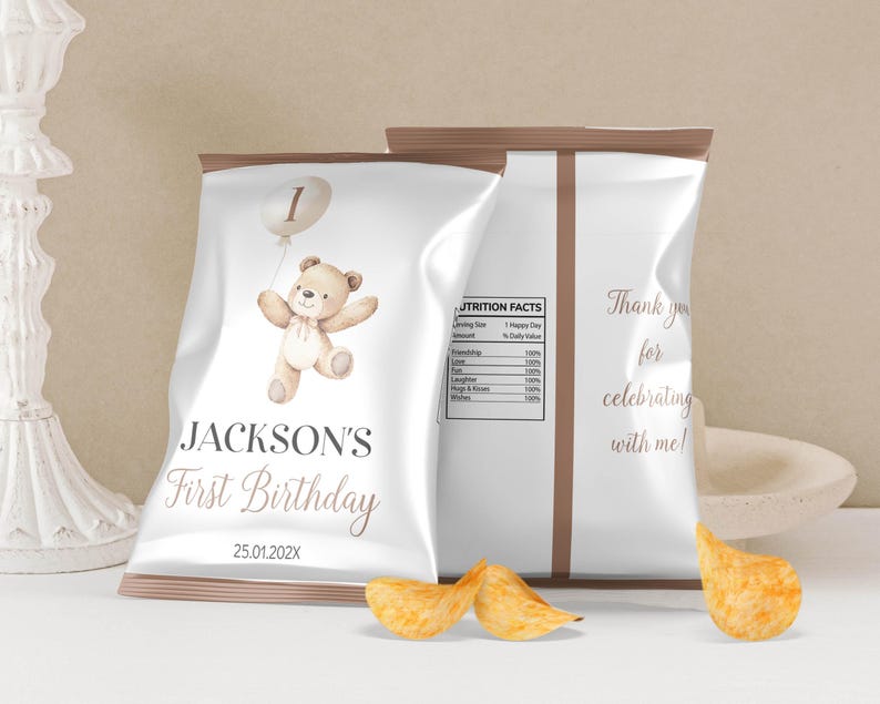 May include: White chip bag with a brown border. The front of the bag has a cartoon illustration of a teddy bear holding a balloon with the number 1 on it. The text "JACKSON'S First Birthday 25.01.202X" is printed on the bag.