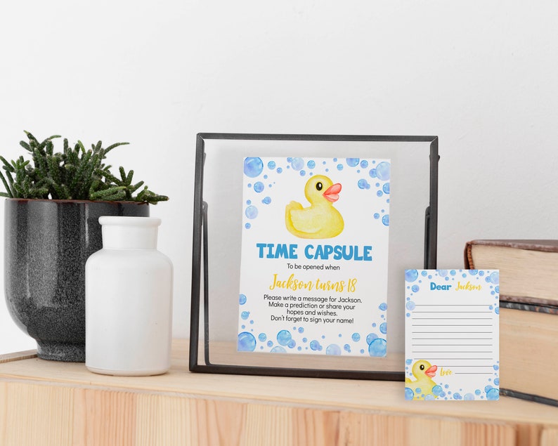 May include: A time capsule card with a yellow rubber ducky and blue bubbles. The card says "Time Capsule" and "To be opened when Jackson turns 18". There is a separate card with the text "Dear Jackson" and a blank space for writing a message.