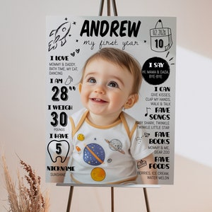 Pode incluir: Um cartaz de marcos brancos com uma fotografia central de um beb&eacute; a usar um body com tema espacial. O texto inclui o nome Andrew, my first year, e v&aacute;rias estat&iacute;sticas como 28 inches, 30 pounds e 5 dentes, juntamente com gr&aacute;ficos espaciais.