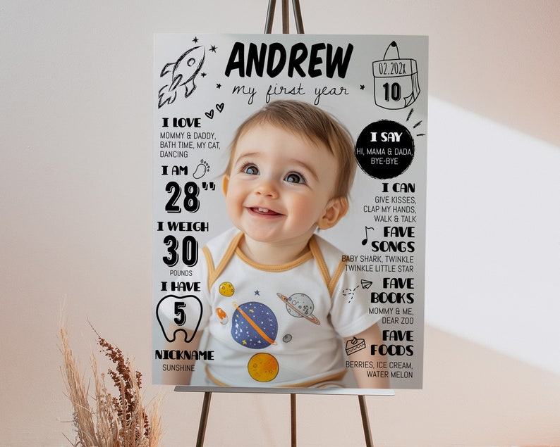 Pode incluir: Um cartaz de marcos brancos com uma fotografia central de um beb&eacute; a usar um body com tema espacial. O texto inclui o nome Andrew, my first year, e v&aacute;rias estat&iacute;sticas como 28 inches, 30 pounds e 5 dentes, juntamente com gr&aacute;ficos espaciais.