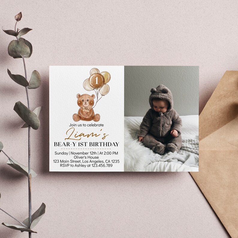 Op de afbeelding: Een rechthoekige verjaardagsuitnodiging met een aquarelillustratie van een bruine teddybeer die beige ballonnen met het cijfer 1 vasthoudt. De tekst luidt Liam's BEAR-Y 1ST BIRTHDAY, zondag 12 november, en bevat een foto van een kind.