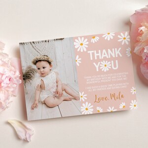 May include: Pink thank you card with white daisies and yellow centers. The card has the text "THANK YOU" in white with a daisy in the "O". The text below reads "Thank you so much for celebrating my birthday with me and for the wonderful present you gave me. I had such a good time playing with all my friends and eating cake! Love. Mila"