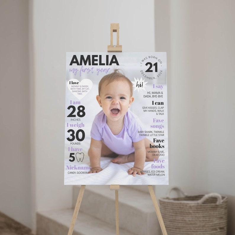 May include: A white and purple first birthday sign for a baby girl named Amelia. The sign includes a photo of the baby, her age, height, weight, favorite things, and nicknames. The sign says "Amelia, my first year".