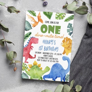 May include: A rectangular birthday invitation card featuring watercolor illustrations of a red, yellow, green, and blue dinosaur, with green tropical leaves and text that reads: COME JOIN US FOR ONE dino-mite time! HENRY'S 1ST BIRTHDAY SATURDAY NOVEMBER 12TH AT 2:00 PM HENRY'S HOUSE 123 MAIN STREET BOSTON 1235 RSVP TO ASHLEY AT 123.456.789