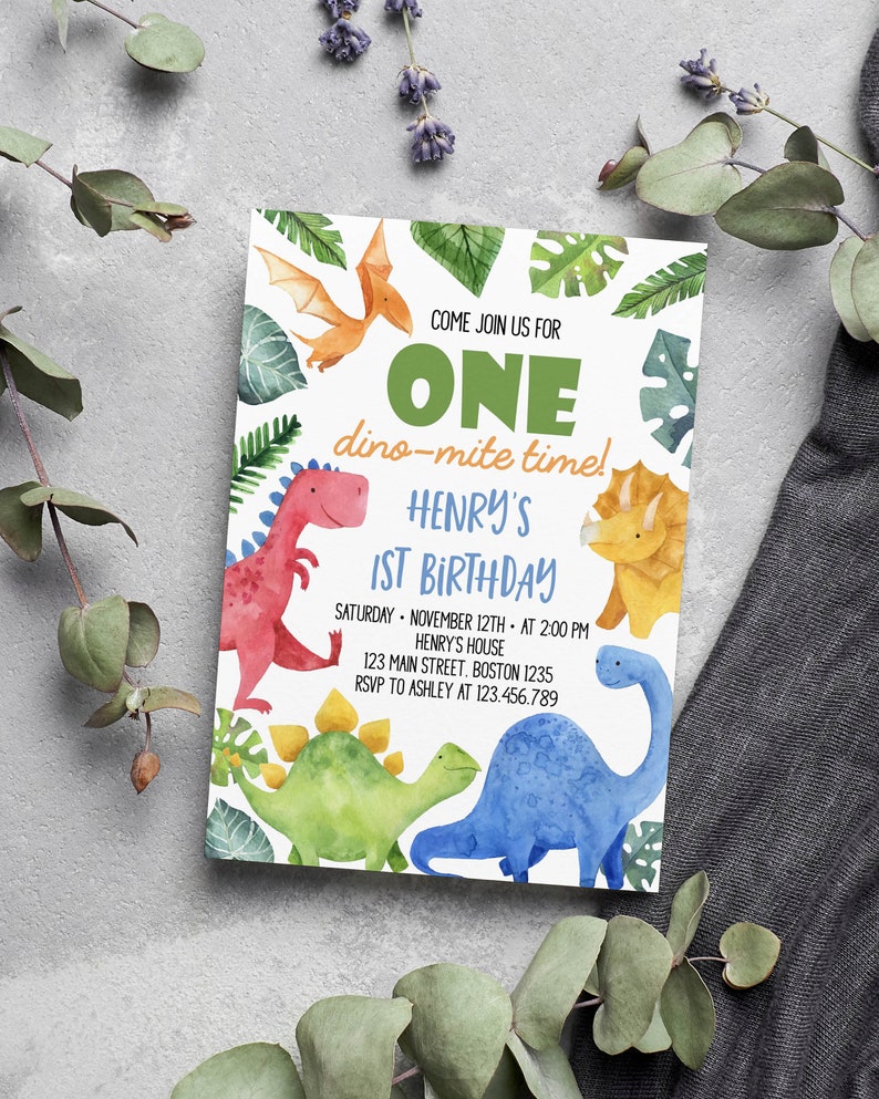 May include: A rectangular birthday invitation card featuring watercolor illustrations of a red, yellow, green, and blue dinosaur, with green tropical leaves and text that reads: COME JOIN US FOR ONE dino-mite time! HENRY'S 1ST BIRTHDAY SATURDAY NOVEMBER 12TH AT 2:00 PM HENRY'S HOUSE 123 MAIN STREET BOSTON 1235 RSVP TO ASHLEY AT 123.456.789