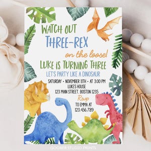 May include: A birthday party invitation with a dinosaur theme. The invitation reads "Watch Out Three-Rex on the loose! Luke is turning three." Colorful watercolor illustrations of dinosaurs and tropical leaves surround the text. The invitation includes party details.