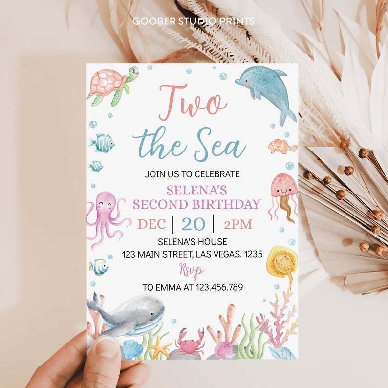 May include: A light blue and pink invitation card with the text "Two the Sea" and "Selena's Second Birthday" with a date and time of December 20th at 2 PM. The card features a variety of sea creatures including a turtle, dolphin, octopus, jellyfish, and a whale.