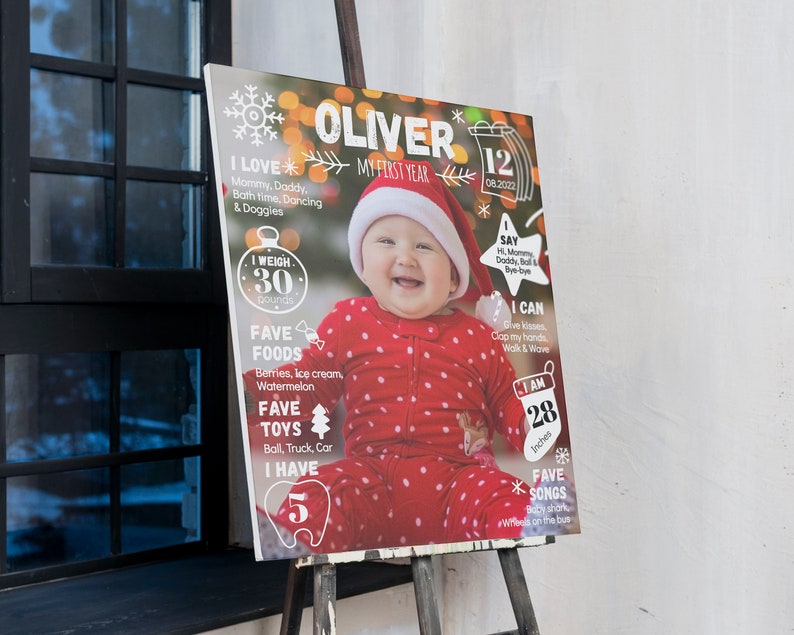 Puede incluir: Un tablero de hitos rectangular con la foto de un beb&eacute; con gorro de Pap&aacute; Noel rojo y pijama de lunares. El tablero muestra texto que incluye Oliver, My First Year, 12.08.2022, I Love, I Weigh 30 pounds, I Say, I Can, Fave Foods, Fave Toys, I Have 5, I Am 28 inches y Fave Songs.