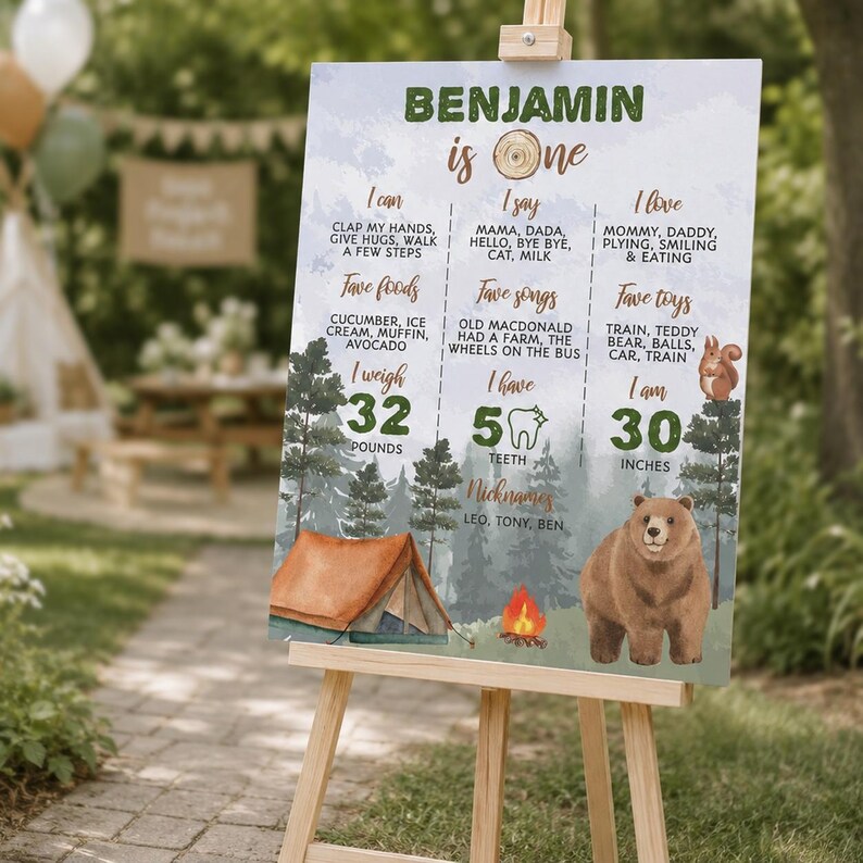 May include: A rectangular milestone birthday sign for a one-year-old named Benjamin, featuring a forest theme with a brown bear, a tent, and a campfire. The text lists milestones including weight in pounds, height in inches, and favorite things.