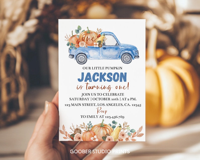 May include: A rectangular birthday invitation card featuring a blue pickup truck carrying pumpkins and the text: OUR LITTLE PUMPKIN JACKSON is turning one! JOIN US TO CELEBRATE SATURDAY | OCTOBER 10th | AT 2 PM. 123 MAIN STREET, LOS ANGELES, CA. 12345 RSVP TO EMILY AT 123.456.789.
