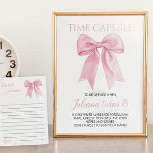 May include: A pink and gold time capsule card with a pink bow and the text "Time Capsule" and "Juliana turns 18". The card includes instructions to write a message for Juliana, make a prediction, or share hopes and wishes.  The card also includes a blank card with the text "Dear Juliana" and "Love".