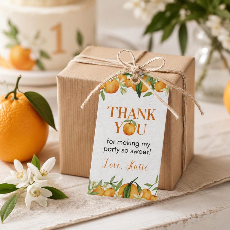 Pu&ograve; includere: Un'etichetta regalo rettangolare in carta bianca legata con spago marrone a una scatola marrone. L'etichetta presenta illustrazioni di arance ad acquerello, foglie verdi e il testo: THANK YOU for making my party so sweet! Love, Katie.