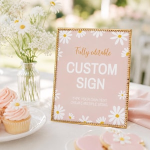 May include: A rectangular sign in a gold beaded frame featuring a light pink background with white daisy illustrations. The text reads: Fully editable, CUSTOM SIGN, TYPE YOUR OWN TEXT, CREATE MUTIPLE SIGNS. The sign is displayed in a vertical orientation.