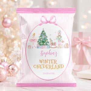 May include: A pink and white striped snack bag featuring a central oval graphic with a ballerina, a Christmas tree, a nutcracker, and a rocking horse. The text reads Sophia's WINTER ONEDERLAND and 16.12.202X, accented by a pink bow at the top.