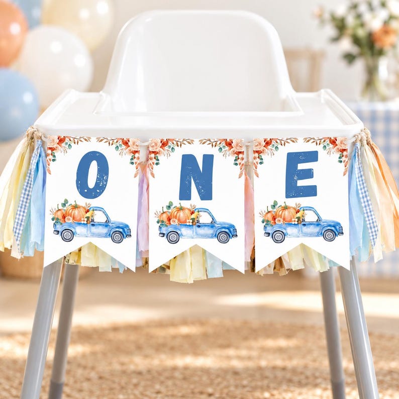May include: A high chair banner featuring three white pennants with the blue letters O, N, and E. Each pennant displays a watercolour illustration of a blue pickup truck carrying orange pumpkins, accented with autumn leaves and tassels.