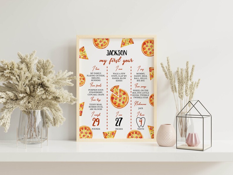 May include: A white printable poster with a pizza theme for a baby's first birthday. The poster has a red title "JACKSON my first year". It lists the baby's favorite foods, activities, songs, and measurements: 29 pounds, 27 inches, and 4 teeth.