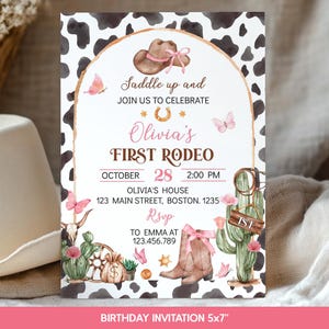 May include: A rectangular birthday invitation card featuring a black and white cow print border and a central arch. The text reads: Saddle up and JOIN US TO CELEBRATE Olivia's FIRST RODEO OCTOBER 28 2:00 PM OLIVIA'S HOUSE 123 MAIN STREET, BOSTON. 1235 RSVP TO EMMA AT 123.456.789. Illustrations include a brown cowboy hat with a pink ribbon, pink butterflies, a horseshoe, a cactus, a cow skull, a money bag, and brown cowboy boots.
