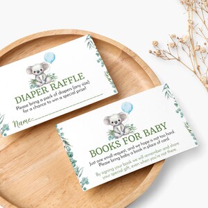 K&ouml;nnte beinhalten: Zwei rechteckige wei&szlig;e Karten mit einem Aquarell-Koala, der einen blauen Ballon h&auml;lt, gr&uuml;nen Eukalyptusbl&auml;ttern und Text. Eine Karte zeigt DIAPER RAFFLE und die andere BOOKS FOR BABY, inklusive gedruckter Anweisungen und einer Zeile f&uuml;r einen Namen.