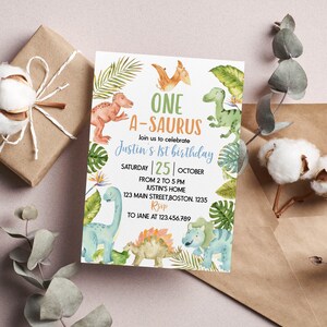 Op de afbeelding: Een rechthoekige verjaardagsuitnodigingskaart met aquarelillustraties van diverse dinosaurussen en tropische bladeren. De tekst luidt: ONE A-SAURUS, join us to celebrate Justin's 1st birthday, SATURDAY 25 OCTOBER, FROM 2 TO 5 PM, JUSTIN'S HOME, 123 MAIN STREET, BOSTON. 1235, RSVP TO JANE AT 123.456.789.