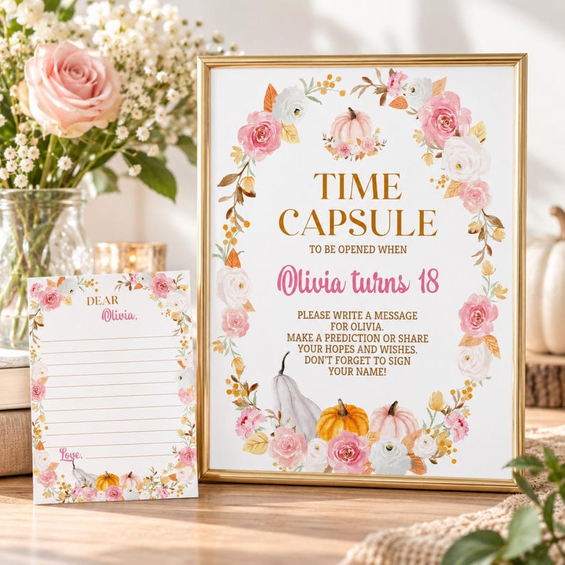 K&ouml;nnte beinhalten: Ein goldgerahmtes Schild und eine passende Karte mit einem Blumenkranz aus rosa und wei&szlig;en Rosen sowie orangefarbenen und wei&szlig;en K&uuml;rbissen. Das Schild tr&auml;gt die Aufschrift: TIME CAPSULE TO BE OPENED WHEN Olivia turns 18. PLEASE WRITE A MESSAGE FOR OLIVIA.