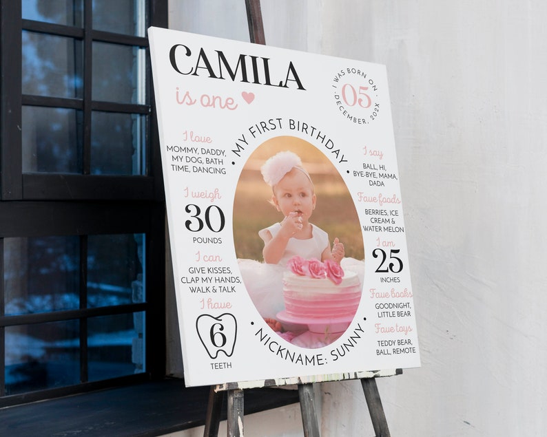 May include: A white rectangular birthday milestone sign featuring the name CAMILA, a central oval photo of a child with a cake, and text detailing birth date, weight of 30 pounds, height of 25 inches, 6 teeth, and favorite things.