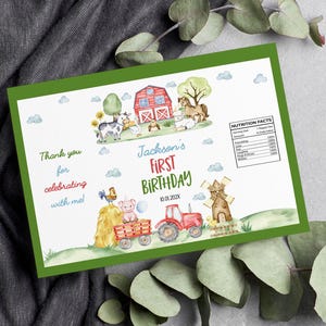 May include: A rectangular card with a green border featuring watercolor farm illustrations including a red barn, tractor, windmill, and animals. Text reads Jackson's FIRST BIRTHDAY 10.01.202X, Thank you for celebrating with me, and a Nutrition Facts label.