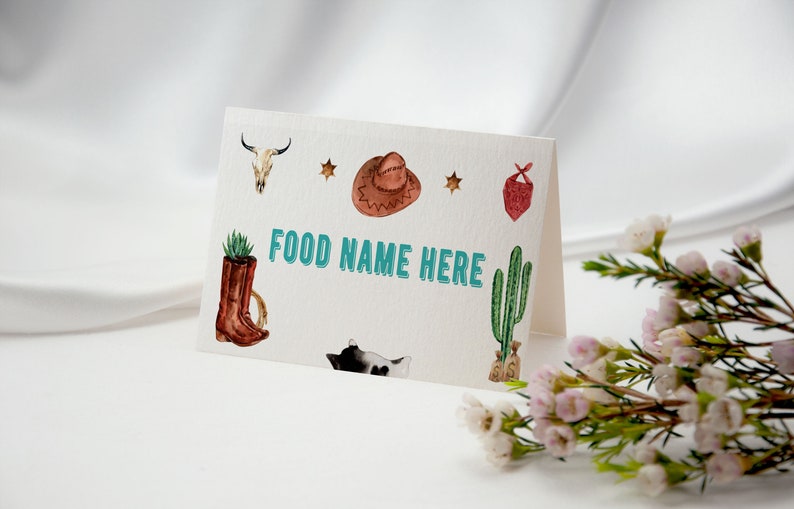 K&ouml;nnte beinhalten: Eine gefaltete wei&szlig;e Karte mit dem Text FOOD NAME HERE in t&uuml;rkisfarbenen Buchstaben. Die Karte ist mit Aquarellillustrationen eines Kuhsch&auml;dels, eines braunen Cowboyhuts, zwei Sternen, einem roten Bandana, einem Stiefel und einem Kaktus verziert.