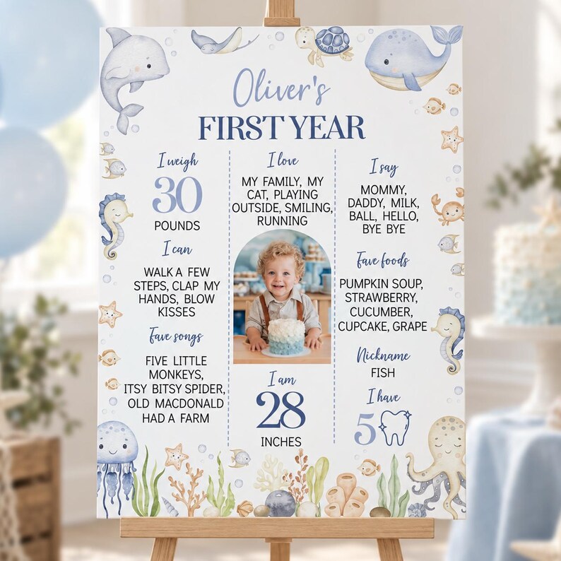 May include: A white milestone birthday sign titled Oliver's FIRST YEAR featuring blue text, a central photo of a child, and watercolor illustrations of sea creatures including a dolphin, whale, octopus, jellyfish, and seahorses with ocean plants.
