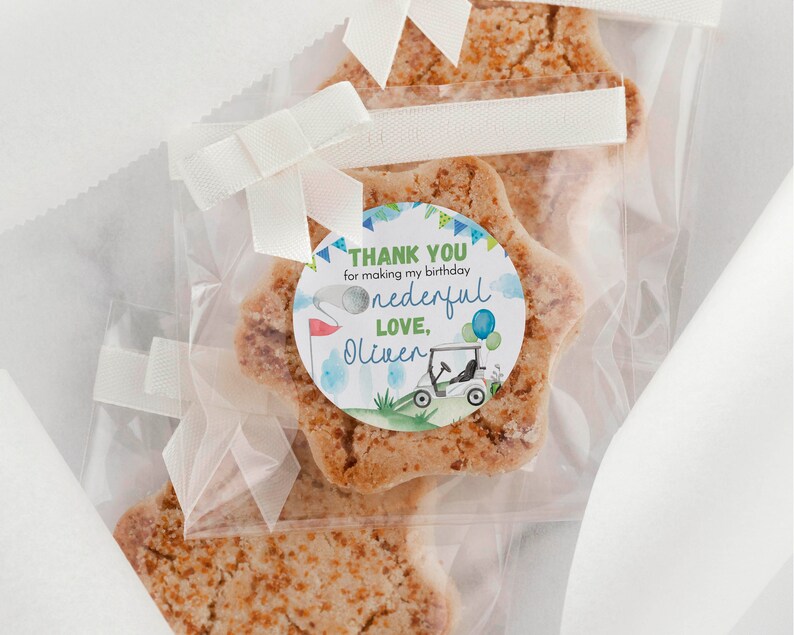 May include: Star-shaped cookies packaged in clear plastic bags with white ribbon bows. Each bag features a round sticker with a golf cart illustration, blue balloons, and text that reads: THANK YOU for making my birthday onederful LOVE, Oliver.