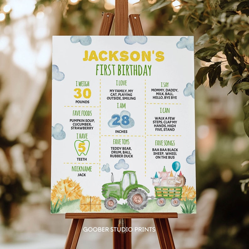 May include: A white birthday milestone sign for Jackson featuring yellow and green text, blue watercolor clouds, and a green tractor pulling a trailer with farm animals. The sign lists stats including 30 pounds, 28 inches, and 5 teeth.