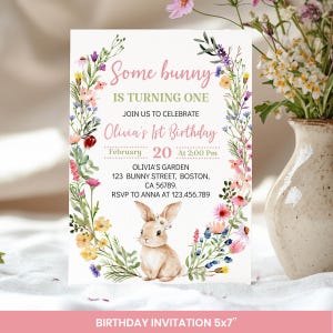 May include: A rectangular birthday invitation card featuring a watercolor floral wreath surrounding a central illustration of a small brown bunny. The text reads: Some bunny IS TURNING ONE JOIN US TO CELEBRATE Olivia's 1st Birthday February 20 At 2:00 Pm OLIVIA'S GARDEN 123 BUNNY STREET, BOSTON, CA 56789. RSVP TO ANNA AT 123.456.789.