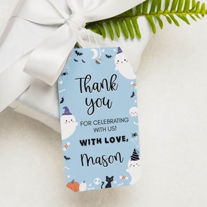 Pu&ograve; includere: Un'etichetta regalo rettangolare azzurra a tema Halloween con fantasmi bianchi che indossano cappellini da festa, gatti neri, zucche, pipistrelli e ragnatele. Il testo recita Thank you FOR CELEBRATING WITH US! WITH LOVE, Mason in carattere nero.