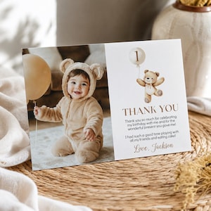 May include: A rectangular thank you card featuring a photo of a child in a tan bear-ear jumpsuit holding a beige balloon. The right side displays a watercolor teddy bear with a balloon, the text THANK YOU, and a message signed Love, Jackson.