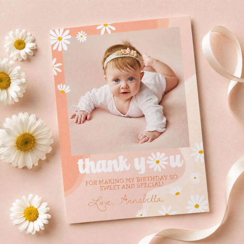 May include: A rectangular thank you card with a peach-colored border featuring white daisy illustrations. The center displays a photograph of a baby wearing a white long-sleeved outfit and a floral headband. Text reads: thank you FOR MAKING MY BIRTHDAY SO SWEET AND SPECIAL! Love, Annabella.