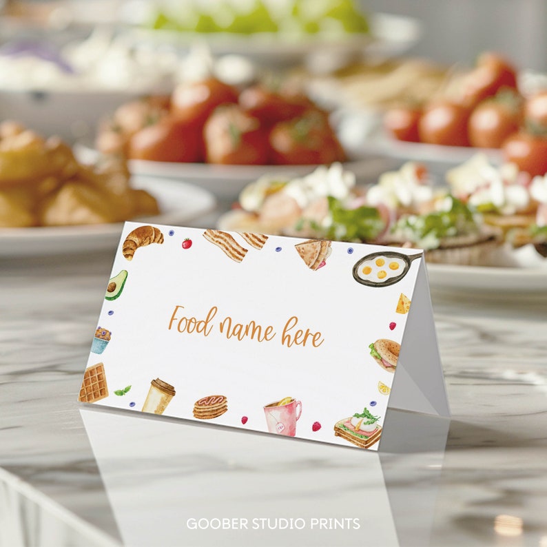 Pu&ograve; includere: Carta bianca con un disegno ad acquerello di cibi per la colazione attorno al bordo. Il testo "Nome del cibo qui" &egrave; scritto in marrone al centro della carta.