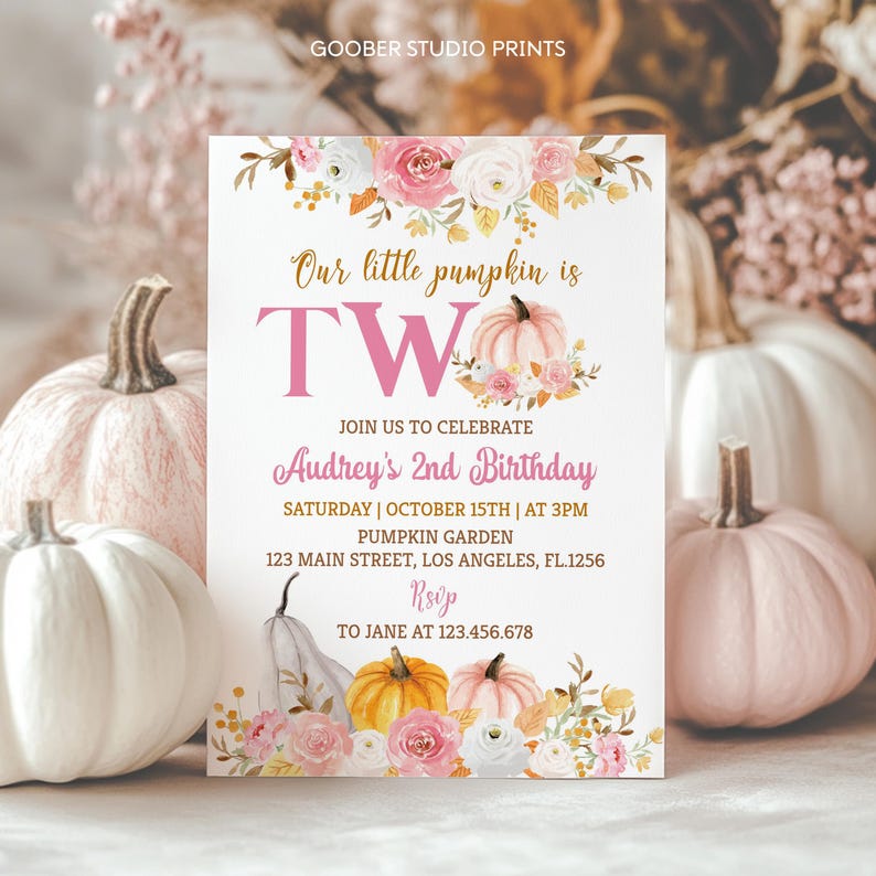 May include: A white invitation card with the text "Our little pumpkin is TWO" in pink and gold. The card is decorated with floral and pumpkin illustrations. The invitation is for Audrey's 2nd birthday, with the date, time, and location.