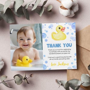 K&ouml;nnte beinhalten: Eine Dankeskarte mit einem blauen und wei&szlig;en Aquarellhintergrund, auf dem eine gelbe Gummi-Ente und blaue Blasen zu sehen sind. Die Karte enth&auml;lt ein Foto eines kleinen Jungen in der Badewanne mit einer gelben Gummi-Ente. Der Text auf der Karte lautet: "Vielen Dank, dass ihr meinen Geburtstag mit mir gefeiert habt und f&uuml;r das tolle Geschenk, das ihr mir gemacht habt! Ich hatte so viel Spa&szlig; beim Spielen mit all meinen Freunden und beim Kuchen essen! Liebe Gr&uuml;&szlig;e, Jackson."