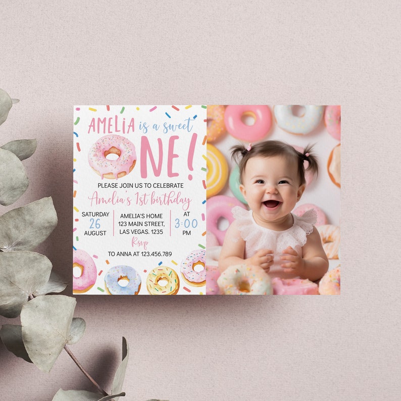 May include: A pink and white donut-themed first birthday party invitation with a photo of a baby girl surrounded by donuts. The invitation says "Amelia is a sweet one!" and includes the date, time, and location of the party.