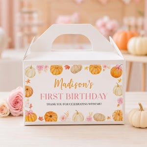 May include: A white cardboard gable box featuring a decorative border of watercolor pumpkins, autumn leaves, and pink roses. The text reads Madison's FIRST BIRTHDAY THANK YOU FOR CELEBRATING WITH ME in gold and black lettering on the front panel.