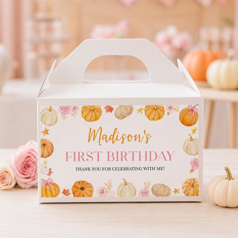 May include: A white cardboard gable box featuring a decorative border of watercolor pumpkins, autumn leaves, and pink roses. The text reads Madison's FIRST BIRTHDAY THANK YOU FOR CELEBRATING WITH ME in gold and black lettering on the front panel.