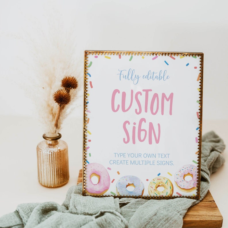 K&ouml;nnte beinhalten: Ein rechteckiges Schild in einem Metallrahmen mit wei&szlig;em Hintergrund, bunten Streuseln und vier Aquarell-Donuts am unteren Rand. Der Text lautet Fully editable CUSTOM SIGN TYPE YOUR OWN TEXT CREATE MULTIPLE SIGNS.