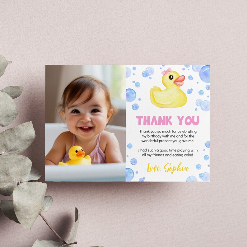 May include: A rectangular thank you card featuring a photograph of a smiling child in a bathtub with a yellow rubber duck. The right side displays a watercolor yellow rubber duck with a pink bow, blue bubbles, and the text Thank You, Sophia.