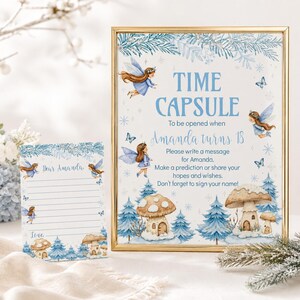 May include: A gold-framed sign and a matching card featuring blue watercolor illustrations of fairies, mushrooms, and pine trees. The sign reads: TIME CAPSULE To be opened when Amanda turns 18. Please write a message for Amanda.