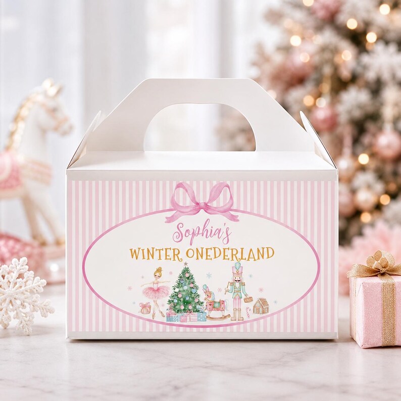 May include: A white gable box featuring a pink striped pattern and a central oval graphic. The graphic displays a pink bow, the text "Sophia's WINTER ONEDERLAND," and illustrations of a ballerina, a Christmas tree, a nutcracker, and a rocking horse.