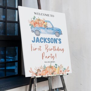 May include: A white rectangular birthday sign featuring a watercolour illustration of a blue pickup truck carrying pumpkins and flowers. The text reads: WELCOME TO one JACKSON'S First Birthday Party! 10.10.202X. The bottom features orange pumpkins.