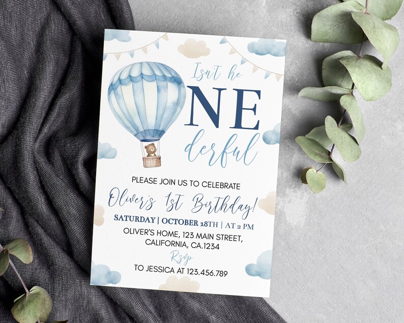 Pu&ograve; includere: Un biglietto d'invito rettangolare con una mongolfiera ad acquerello, un orsacchiotto nel cesto, nuvole blu e beige e festoni. Il testo recita: Isn't he ONEderful, PLEASE JOIN US TO CELEBRATE Oliver's 1st Birthday, SATURDAY | OCTOBER 18TH | AT 2 PM, OLIVER'S HOME, 123 MAIN STREET, CALIFORNIA, CA.1234, RSVP TO JESSICA AT 123.456.789.
