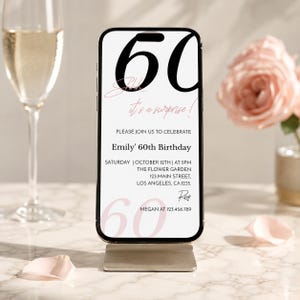 K&ouml;nnte beinhalten: Ein Smartphone zeigt eine digitale Geburtstagseinladung auf wei&szlig;em Hintergrund. Der Text lautet 60, Shhh... it's a surprise!, PLEASE JOIN US TO CELEBRATE Emily' 60th Birthday, SATURDAY | OCTOBER 12TH | AT 5PM, THE FLOWER GARDEN, 123 MAIN STREET, LOS ANGELES, CA.1235, RSVP MEGAN AT 123.456.789.